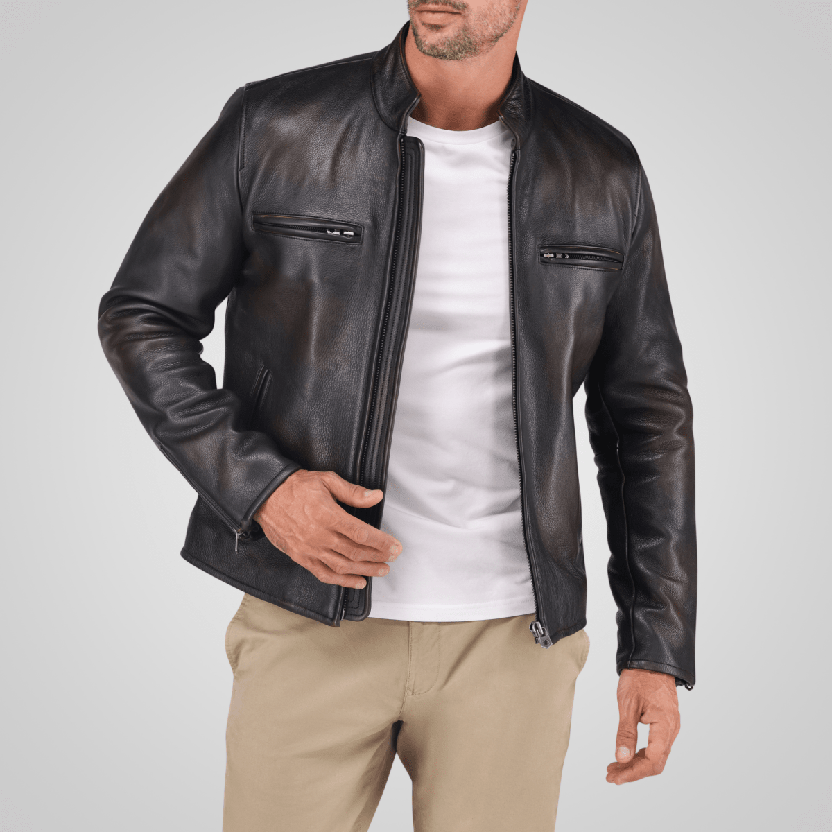 A man wearing a black leather jacket with a quilted design, chest and inner pockets, and a white shirt underneath.