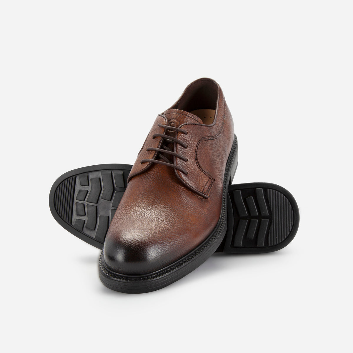 Pair of brown Oxford Derby Shoes, one showing the lug rubber sole