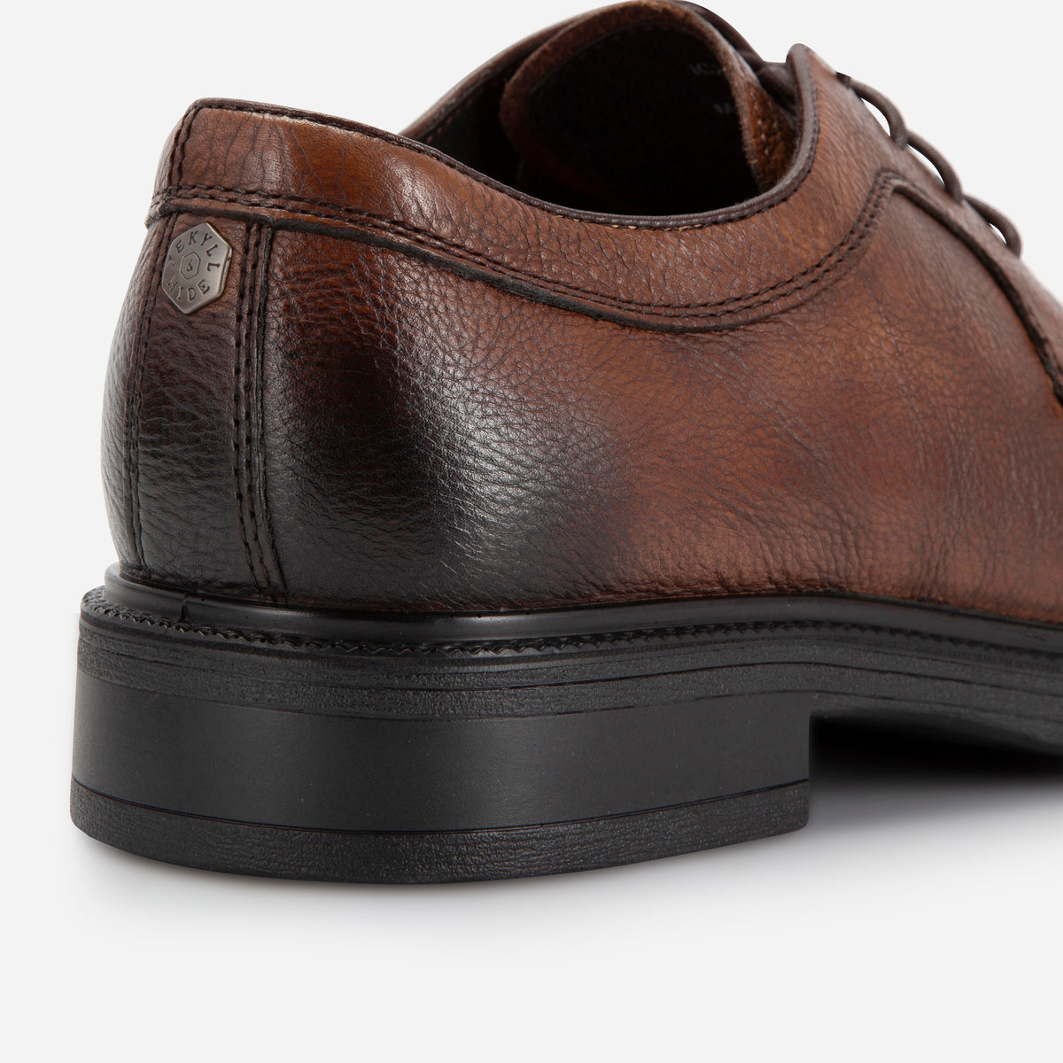 Close-up of the brown Oxford Derby Shoe's pebbled heel counter and logo