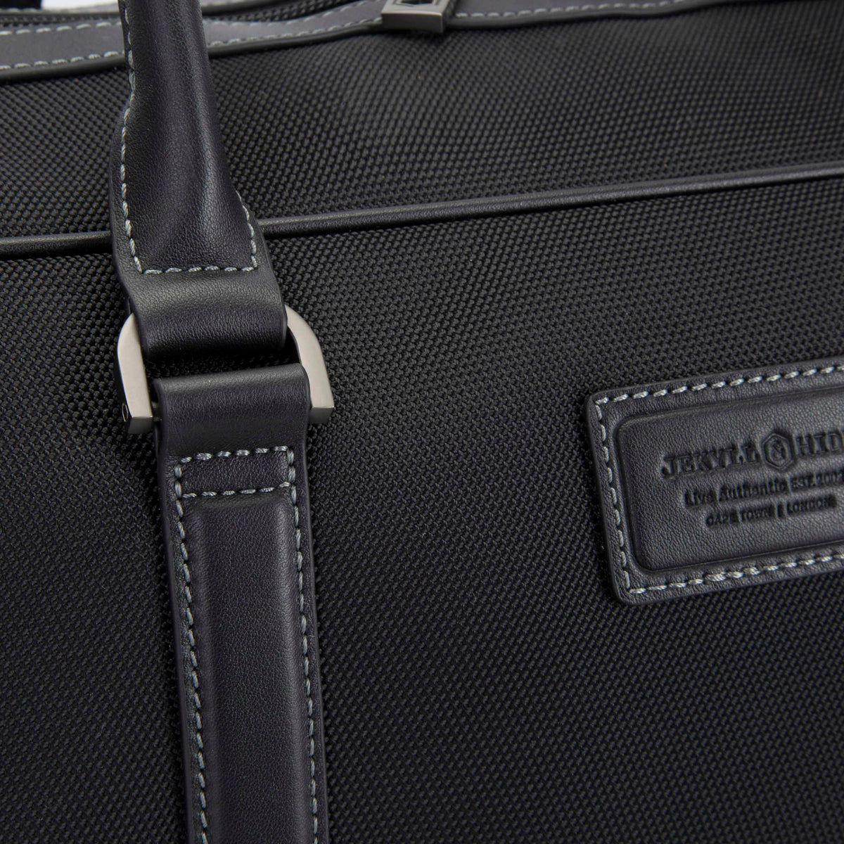Close-up of the 1680D nylon, leather grab handle and debossed leather patch on the Tokyo golf duffle, Jekyll & Hide