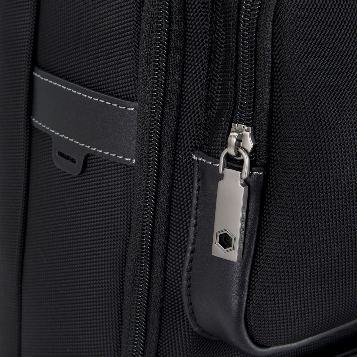 Close-up of the Tokyo Large Backpack's leather trim and logo zip pull